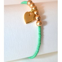 Bright green beaded friendship bracelet with gold love heart charm.